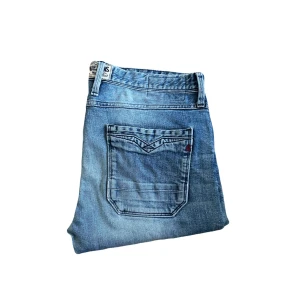 Replay jeans - Säljer ett par klassiska ljusblå jeans från Replay i rak modell. Jeansen har snygga slitningar, fem fickor och röda broderade detaljer på insidan av linningen. Perfekta för dig som gillar en avslappnad och tidlös look. Midja 44cm! Uppsydda för att motsvara L30 men kolla längdmåttet! Jag skickar ej bild när jag bär plaggen och jag vet ej vilken längd och vikt de passar då jag inte prövar kläderna jag säljer, så för storlek hänvisar jag till måtten och passform att man googlar på modellnamn etc 😃