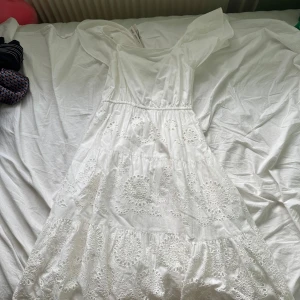 Vit broderad långklänning från Zara - Superfin vit långklänning från Zara med broderade detaljer och volanger. Klänningen har korta ärmar och är gjord i bomull, perfekt för sommarens alla tillfällen. Söt och luftig med romantisk känsla och snygg passform.