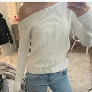 Vit ribbad offshoulder stickad tröja - Superfin vit stickad tröja från Even&Odd med ribbad struktur och offshoulder-design. Långärmad och mjuk, perfekt för lager på lager. Snygg passform som sitter lite lösare och ger en chill vibe. Passar till jeans eller kjol för en trendig look.