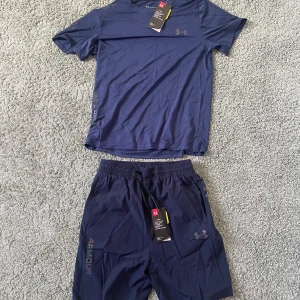 Under armour set - Snygg blå t-shirt från Under Armour med diskret logga på bröstet. Tillverkad i ett lätt och ventilerande syntetmaterial som håller dig sval under träningen. Klassisk passform med korta ärmar och rund hals. Perfekt för dig som gillar sportig stil. Den är i helt nytt skick och säljer den för att den är för stor för mig.
