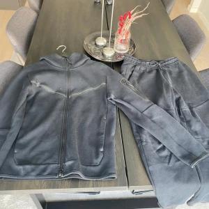 Nike tech  - Hej! Köpte en Nike tech för lite mer än ett år sedan. Har knappt använt den och därför jag säljer den. Nypris för setet är 2224kr (Zalando). Finns ett litet hål på vänster arm på hoodien. Kom dm för bild. Hör gärna av er, bara att fråga om ni har! 