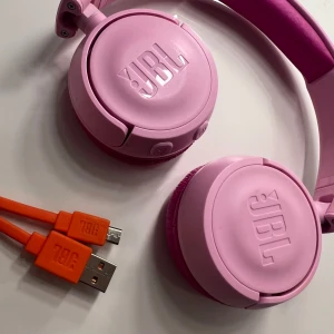 Rosa barn JBL hörlurar med laddare - Rosa barn JBL hörlurar som är i bra skick, har inga defekter och laddar snabbt. Kommer med sin orginala JBL laddare. Laddaren är i bra skick och fungerar som nytt.