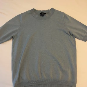 Blå/grön tröja - En stilren och fin blå/grön tröja med korta ärmar. Lite detaljer vid hals, ärmar och midja. Köpt från Lindex och kommer inte mer till användning. Kontakta gärna innan köp!