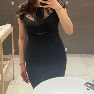 Svart spetsklänning från Guess - Säljer denna supersnygga svarta kortklänning från Guess med spetsdetaljer upptill och vid axlarna. Klänningen har figurnära passform, rund halsringning och dragkedja i ryggen. Perfekt för dig som vill sticka ut med en elegant och modern look. Klänningen ger lite gossip girl vibe✨