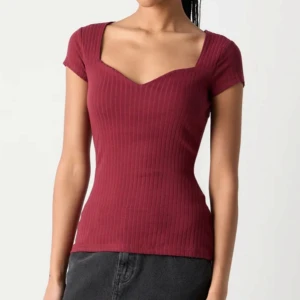 Vinröd ribbad topp med v-ringning - Snygg vinröd topp med korta ärmar och markerad v-ringning. Modellen är ribbad, så snygg! Endast testad 