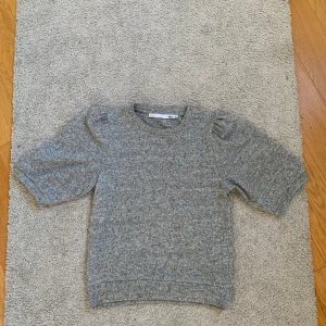 Grå stickad tröja från 157, puffärm - Grå stickad tröja från 157 i storlek XS. Tröjan har korta puffärmar och rund halsringning. 