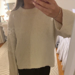 Beige stickad tröja med lång ärm - Enkel och stilren beige stickad tröja med lång ärm och avslappnad passform. Perfekt för lager-på-lager och funkar till både jeans och mjukisbyxor. Mjuk och skön känsla, passar dig som gillar en clean och basic look.