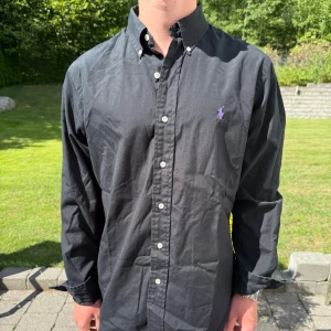 Svart skjorta från Ralph Lauren - Svart Ralph lauren skjorta || Storlek M (Custom Fit) || Skjortan är i bra skick, däremot något fläckig  || mitt pris 499kr || Modellen på bilden är 170cm och väger 62kg || tveka inte på att höra av dig vid frågor eller funderingar 