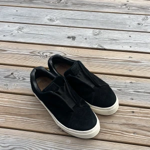 Svarta sneakers från Eytys i mocka - Snygga svarta sneakers från Eytys i mocka med vit platt sula och lila detalj baktill. Slutsålda och eftertraktade!