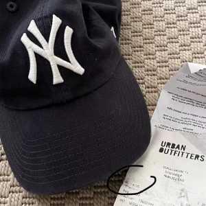NYSKICK Washed New York Yankees keps - Snygg marinblå New York Yankees keps med klassisk böjd skärm och broderad vit NY-logga framtill. Justerbar rem med metallspänne baktill för perfekt passform. Kepsen är i bomull och har en stilren look som passar till allt. 