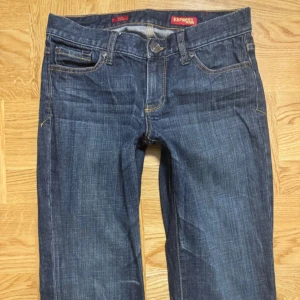 Mörkblå bootcut jeans från Express - Snygga mörkblå jeans från Express med bootcut passform och klassisk femficksdesign. Jeansen har broderade detaljer på bakfickorna och kontrastsömmar. Tillverkade i mjukt denimtyg som sitter skönt hela dagen. storlek 36/38 skulle jag säga, utgå ifrån mått.