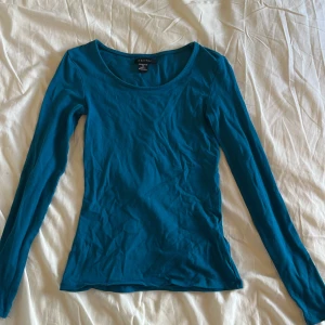 Blå långärmad topp från Amisu - Snygg blå långärmad topp från Amisu med rund halsringning. Modellen är figurnära och passar perfekt till jeans eller kjol. Tillverkad i mjuk bomull som känns skön mot huden. Enkel och stilren design som är lätt att matcha.