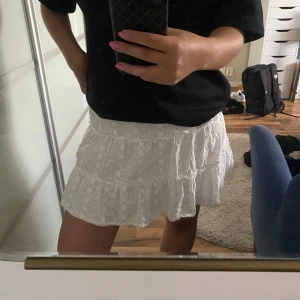 Vit volangkjol - Supersöt vit kortkjol, storlek M. Kjolen har broderade blommor, flera volanger och resår i midjan för en bekväm passform. 