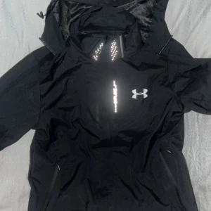 Under Armour Windbreaker - Oavsett om du ska till gymmet, ut i regnet eller bara vill ha en sportig vardagslook den här vattentäta jackan från Under Armour levererar! ☔ UA Storm teknologi vatten och vindavvisande ⚡ Reflekterande detaljer syns i mörkret 🎽 Sportig passform  lika snygg som funktionell 🧥 Justerbar huva + dragkedjefickor 📏 Storlek M  🏃‍♂️ Passa på innan någon annan gör det din perfekta allvädersjacka väntar här!