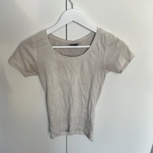 Vit ribbad topp från Firefly XS - En enkel och stilren vit ribbad topp från Firefly i storlek XS. Toppen har rund halsringning och korta ärmar, perfekt för en clean och avslappnad look. Materialet är mjukt och stretchigt för extra komfort.