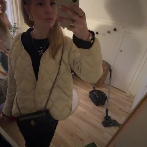 Beige quiltad jacka med kedjedetalj - Säljer en beige quiltad jacka med snyggt mönster och lång ärm. Jackan har en avslappnad passform.  Från uniqlo, köpte på Vinted. Det syns att den är använd men inga hål eller något sånt. 