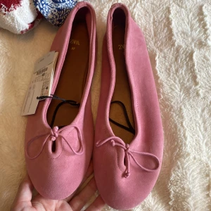 Rosa ballerinaskor i mocka från Zara - Säljer super fina rosa ballerinaskor från Zara i mjuk mocka med rund tå och söt rosettdetalj framtill. Aldrig använda ❤️