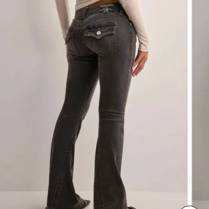 Grå bootcut jeans från True Religion - Snygga grå jeans från True Religion med bootcut passform och klassiska detaljer på bakfickorna. Lågmididjade fint skick!!
