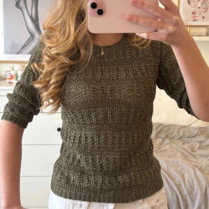 Olivgrön stickad tröja - Säljer en olivgrön stickad tröja med fint strukturmönster. Tröjan har rund halsringning och långa ärmar. Perfekt att styla till både jeans och kjol för en avslappnad look.