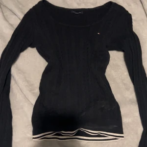 Mörkblå tröja  - Mörkblå kabelstickad tröja med mian detaljer längst ner från tommyhilfiger