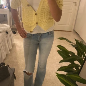 Ljusblå bootcut jeans - Säljer ett par ljusblå bootcut jeans med snygg slitning och hål på ena knät. Jeansen har låg midja och klassisk femficksmodell. 