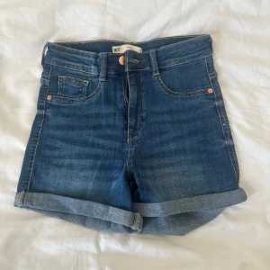 Blå jeansshorts från Gina Tricot - Snygga blå Molly  jeansshorts från Gina Tricot med klassisk femficksdesign och uppvikta benslut. Hög midja och bekväm passform, perfekta för sommardagar. Tidlös denimlook som funkar till allt och är lätt att matcha med dina favoritplagg