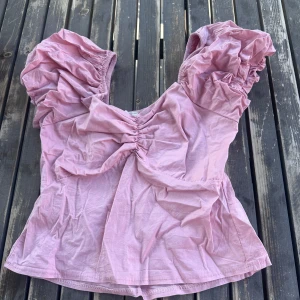 Ljusrosa puffärm blus med rynk - Supersöt ljusrosa blus med stora puffärmar och rynkdetaljer både fram och bak. Köptes i Spanien eller Singapore minns inte riktigt men köptes för runt 299