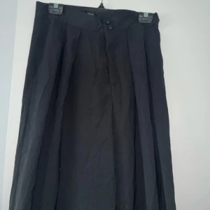Vida svarta kostymbyxor från Shein - Snygga svarta kostymbyxor från Shein med vida ben och hög midja. Byxorna har pressveck framtill och stängs med två knappar i midjan. Perfekta för en clean och stilren look. Materialet känns lätt och luftigt.