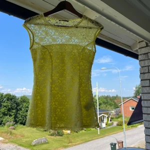 Gul spetsblus med ärmlös design - Säljer en söt gul blus i spets med blommigt mönster. Toppen är ärmlös och har en rund halsringning samt transparenta partier upptill. Perfekt för dig som gillar romantiska och somriga vibes! När man har den på sig så blir den lite utsvängd nertill❣️ Några slitningar som det finns kort på annars är skicket bra