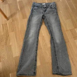 Grå low waisted jeans från Gina Tricot, stl 158  - Snygga grå jeans från Gina Tricot i storlek 158. Jeansen har raka ben, klassisk femficksmodell och coola bakfickor med lock och knapp. Perfekta till en avslappnad streetstil. Materialet är mjukt denim som är skönt att bära hela dagen.
