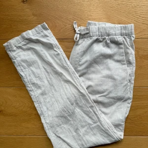  Linnebyxor XS - Snygga ljusgrå linnebyxor från H&M i regular fit. Byxorna har resår och snörning i midjan, sidfickor och en bakficka. Perfekta för en chill och avslappnad stil under varmare dagar. Priset är självklart diskuterbart!