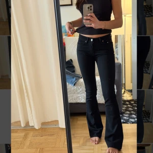 Svarta bootcut jeans från Perfect Jeans - Snygga svarta bootcut jeans från Perfect Jeans med låg midja och klassisk femficksdesign. Jeansen har en tight passform upptill och utsvängda ben, vilket ger en riktigt schysst siluett. Tillverkade i stretchig bomullsblandning för extra komfort.