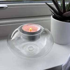 Ljuslykta i glas - Säljer en genomskinlig glaslykta för värmeljus, perfekt för att skapa mysig stämning 💕 Den har en modern, rund design och passar lika bra på fönsterbrädan som på skrivbordet. Aldrig använd - endast testad. Önskar du veta exakta mått? Tveka inte att höra av dig!