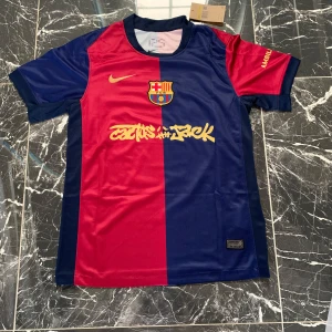 FC Barcelona Lamine Yamal matchtröja - Säljer en officiell FC Barcelona matchtröja från Nike med Lamine Yamal och nummer 19 på ryggen. Tröjan har klassisk halvblå, halvröd design med gula detaljer och klubbmärke på bröstet. Tillverkad i lätt och ventilerande polyester, perfekt för fotbollsplanen.