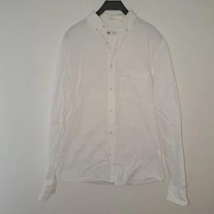 Vit skjorta  - Klassisk vit skjorta i mjuk bomull. Skjortan har lång ärm, bröstficka och knappar framtill. Perfekt för en clean och stilren look, lätt att matcha med jeans eller kostymbyxor.