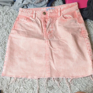 Rosa jeanskjol - Säljer en ljusrosa jeanskjol med fransad nederkant och klassiska fickor både fram och bak. Kjolen har bälteshällor, knapp och dragkedja framtill. Perfekt för dig som gillar en chill och trendig stil. (Lite för stor och lång för mig)☺️