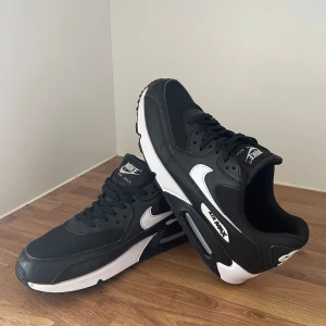 Nike Air Max 90 - Skor - Svarta och vita Nike Air Max 90 sneakers med klassisk siluett, vit swoosh och detaljer. Ovandel i syntet och textil, robust sula med synlig Air Max-dämpning. Perfekta för dig som gillar streetstyle och sportig vibe. De är använda fåtal gånger, så de är i nyskick. Perfekta skor nu inför sommaren då de både är snygga och sköna🦇