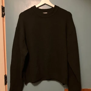 Svart stickad tröja från H&M - En svart stickad tröja från H&M i storlek M. Tröjan har en klassisk rund halsringning och långa ärmar. Perfekt för lager-på-lager och enkel att matcha med olika outfits. Mjuk och skön känsla som passar till kyligare dagar.