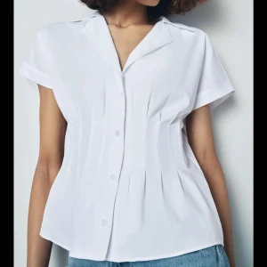 Vit kortärmad blus med indragen midja - Snygg vit blus med korta ärmar och klassisk krage med indragen midja. Endast använd 1 gång, nyskick!
