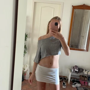 Vit croppad overzised T-shirt som hänger på ena axeln - Snygg croppad overzised T-shirt med one shoulder. Perfekt till dig som dansar eller dig som bara vill kunna vara ute i sommar utan att svettas. Luftig och går att styla med mycket. Kan även användas till mjukis plagg då den är väldigt mjuk och skön!