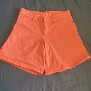 Korallfärgade shorts från Cieni XS - Snygga korallfärgade shorts från Cieni i storlek XS. De har klassisk femficksdesign, bälteshällor och dragkedja framtill. Modellen är lite lösare i benen och passar perfekt till varma dagar. Materialet känns mjukt och skönt, troligtvis bomull.