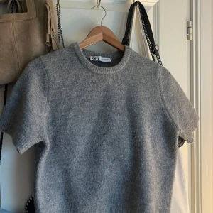 Grå stickad kortärmad tröja Zara - Mysig grå stickad tröja från Zara med korta ärmar och rund halsringning. Perfekt för lager-på-lager och enkel att styla till både jeans och kjol. Mjuk och skön känsla tack vare det stickade materialet. Ganska liten till storlek, alltså spänd men den är gjord så!!🩷