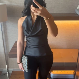 Zara topp - Supersnygg svart halterneck topp i satin med draperad front och öppen rygg som man knyter. Endast använd 1 gång. 