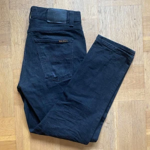 Svarta Nudie Jeans - Säljer ett par svarta Nudie Jeans. Jeansen är raka i passformen, har klassisk femficksdesign och är tillverkade i 100% bomull. Snygga svarta jeans som funkar till allt och har diskreta detaljer.