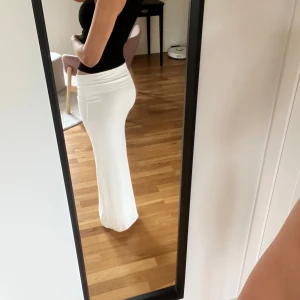 Vit långkjol med stretchig passform - Säljer en vit långkjol med låg midja som man viker ner. Kjolen är enkel och stilren, perfekt till crop tops eller linnen. Materialet är mjukt och stretchigt. Knappt använd💗