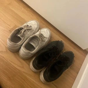 Svarta och vita sneakers med snörning - Två par sneakers i klassisk modell, ett par helsvarta och ett par helvita. Båda har rund tå, platt sula och snörning. Perfekta för en avslappnad streetstil och funkar till det mesta. Materialet är syntet och textil. 20 kr för de båda. Eller 10 kr/st 