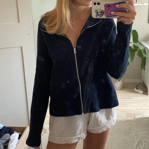 Mörkblå kofta med dragkedja - Mysig mörkblå kofta med hel dragkedja framtill och långärmad modell. Koftan har en enkel och stilren look, perfekt att slänga på sig över en t-shirt. Materialet känns mjukt och lite fluffigt, vilket gör den extra skön att bära.