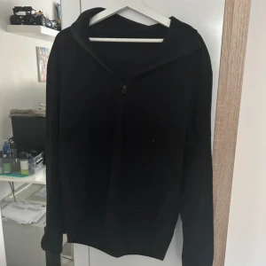 Svart fleece hoodie med half zip - Svart hoodie i mjuk fleece med full zip framtill. Tröjan har lång ärm och en enkel, clean look utan tryck eller mönster. Perfekt för kyliga dagar när du vill ha något bekvämt och stilrent. Passar dig som gillar basic och funktionellt. Jävligt bekväm och passar en laidback enkel stil! 