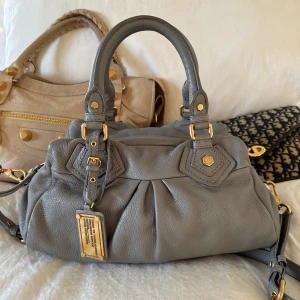 Ljusgrå Q Classic Baby Groove väska! - Köp helst via min vinted, billigare pris pga lägre avgifter @juliavallberg 🤍  Snyggaste gråblå färgade handväskan i äkta läder från Marc by Marc Jacobs. Den ikoniska modellen Q Classic Baby Groove! En populär och eftertraktad vintagemodell med gulddetaljer och dubbla handtag. Väskan är i fint skick men det är en tuggumifläck på insidan av innerfickan (se bild)🤍  Mått: 34x18x12 cm (undersida) Kan hämtas hemma hos mig i Nacka eller skickas 🤍