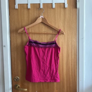 Rosa linnetopp från KappAhl - Snygg rosa linnetopp från Number One by KappAhl med smala axelband. Toppen har lila sammetsband och små paljettdetaljer längs överdelen. Perfekt för dig som vill ha en färgstark och unik topp till sommaren💗💗